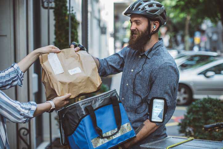Bicycle food delivery commuter with delivering food from a restaurant to a customer, while adhering to IWA 36:2022 contactless delivery specifications.