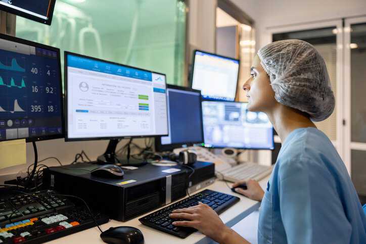 Doctor in the radiology control room and looking at a medical scan to assure compliance to AAMI ESM4 2015 electrical safety specifications.