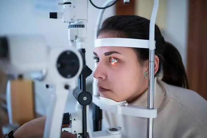 Female patient getting her eyes tested with ophthalmic instruments that adhere to ISO 15004-2:2024 radiation testing specifications.