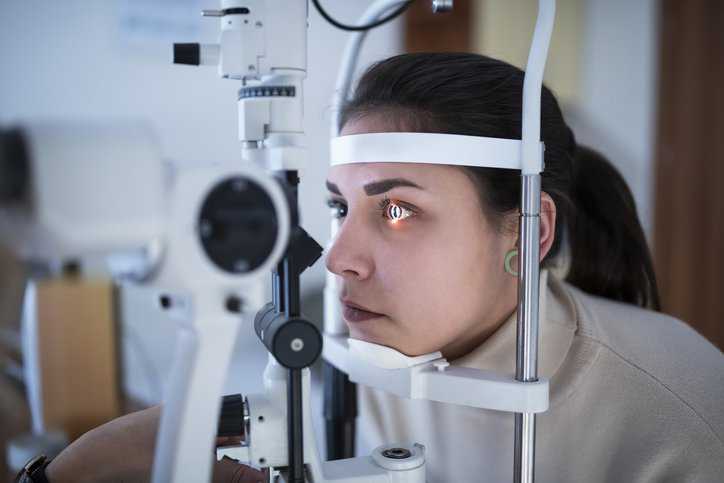 Female patient getting her eyes tested with ophthalmic instruments that adhere to ISO 15004-2:2024 radiation testing specifications.
