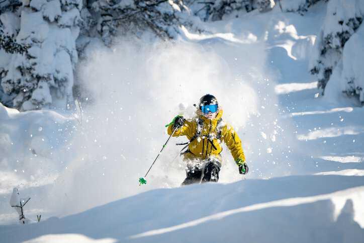 Skier wearing ski googles that adhere to ISO 18527-1:2021 as he skis down the slopes in the winter.
