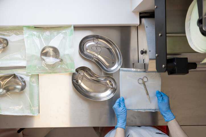 Nurse in the process of sterilization and packaging of surgical instruments, adhering to AAMI TIR17:2024 sterilization of healthcare materials requirements.