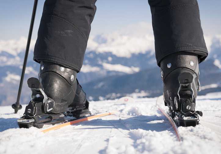 Skier with black boots at top of slope and ready for expert trail with higher DIN setting.