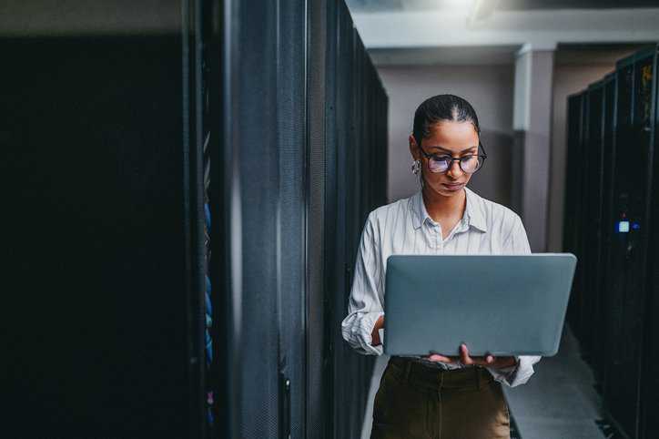 Woman operating her workplace's information technology system according to ISO/IEC 38500:2024 guidelines.