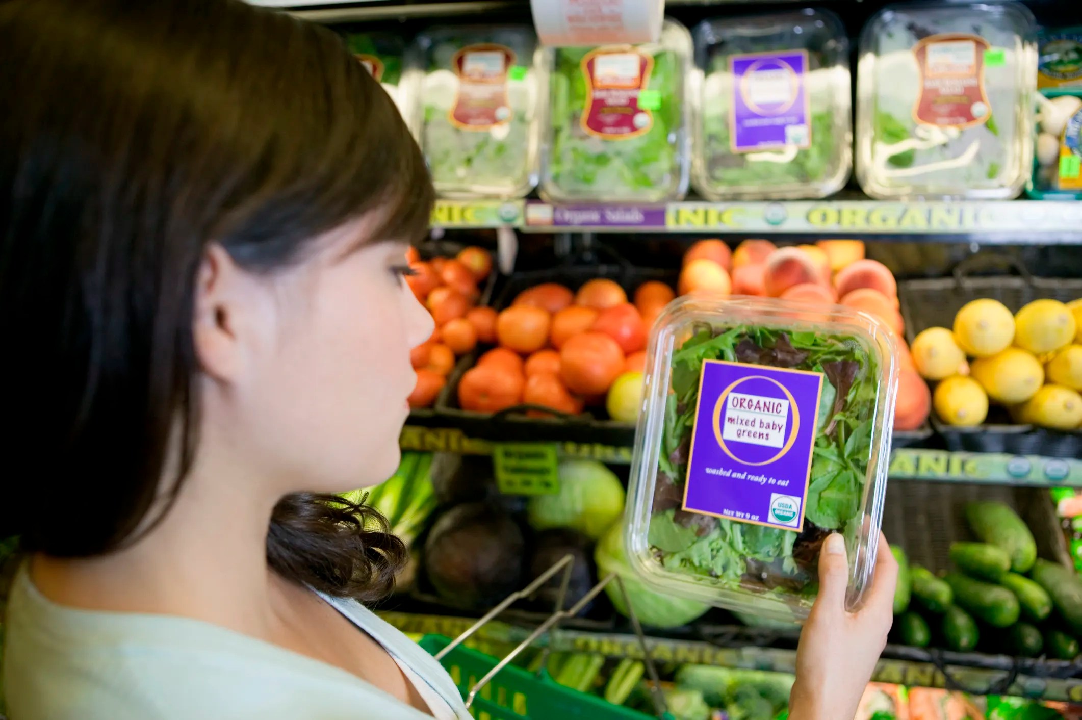 Woman in a grocery store buying USDA labeled organic lettuce that is in compliances with the USDA's National Organic Program (NOP) standards.