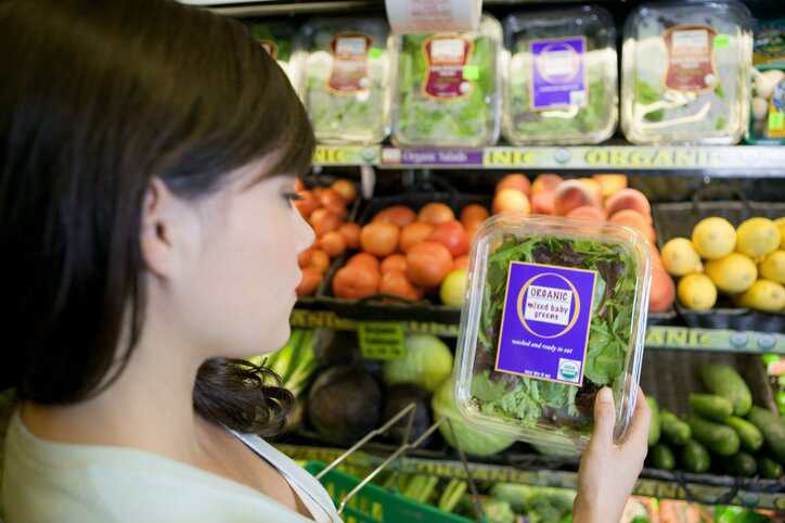 Woman in a grocery store buying USDA labeled organic lettuce that is in compliances with the USDA's National Organic Program (NOP) standards.