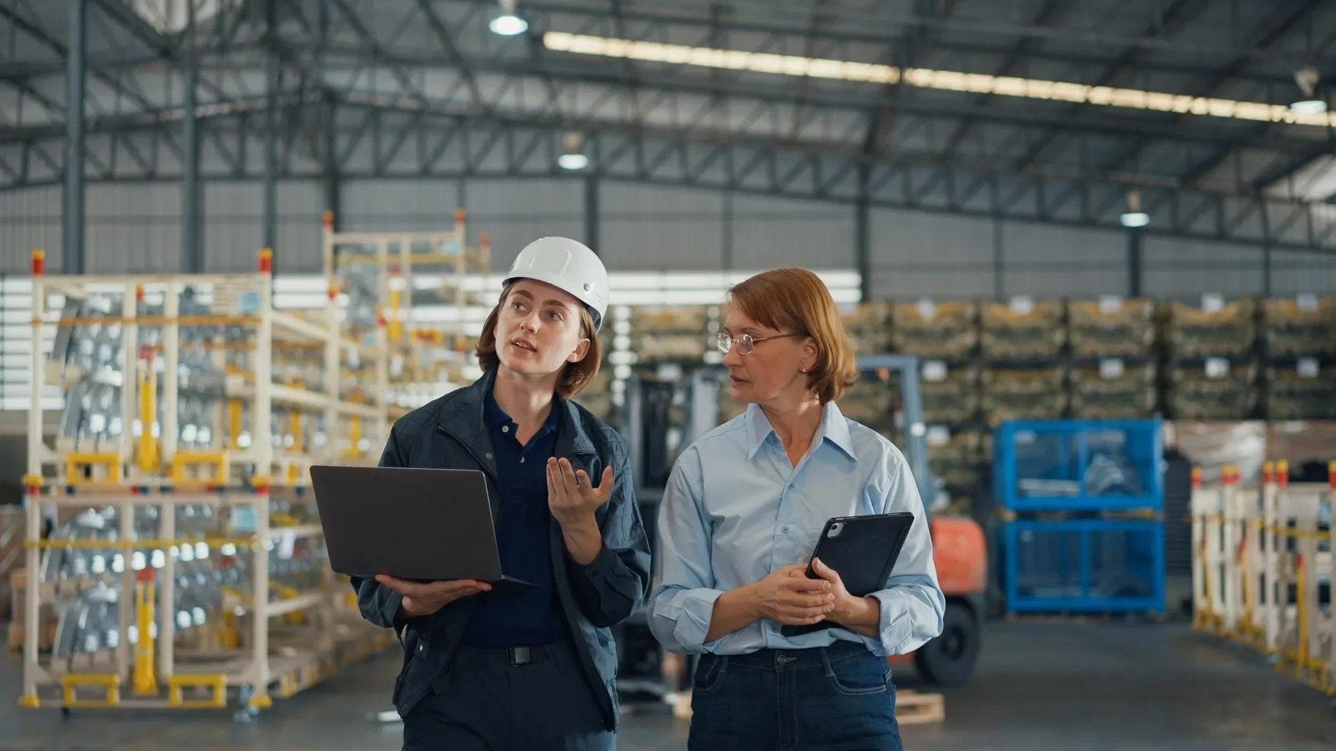 Two workers in a manufacturing assuring that global goods adhere to ISO 900l quality management specifications.