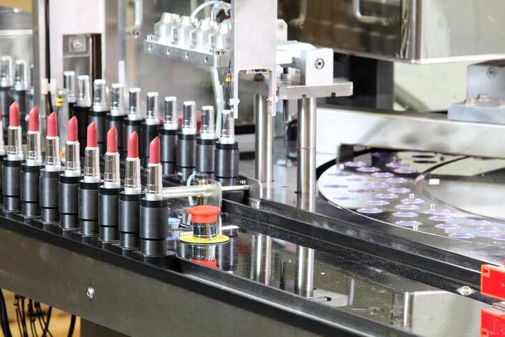 A lipstick packaging machine in a cosmetics factory that adheres to the Good Manufacturing Practices (GMPs) specified in ISO 22716:2007.