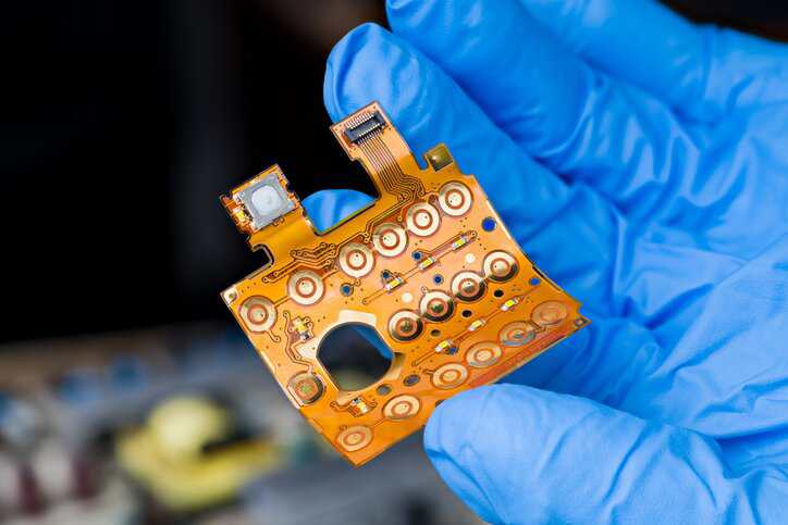 Close-up of an electronic flexible cable with connector on bent plastic circuit board that adheres to IPC-9257.