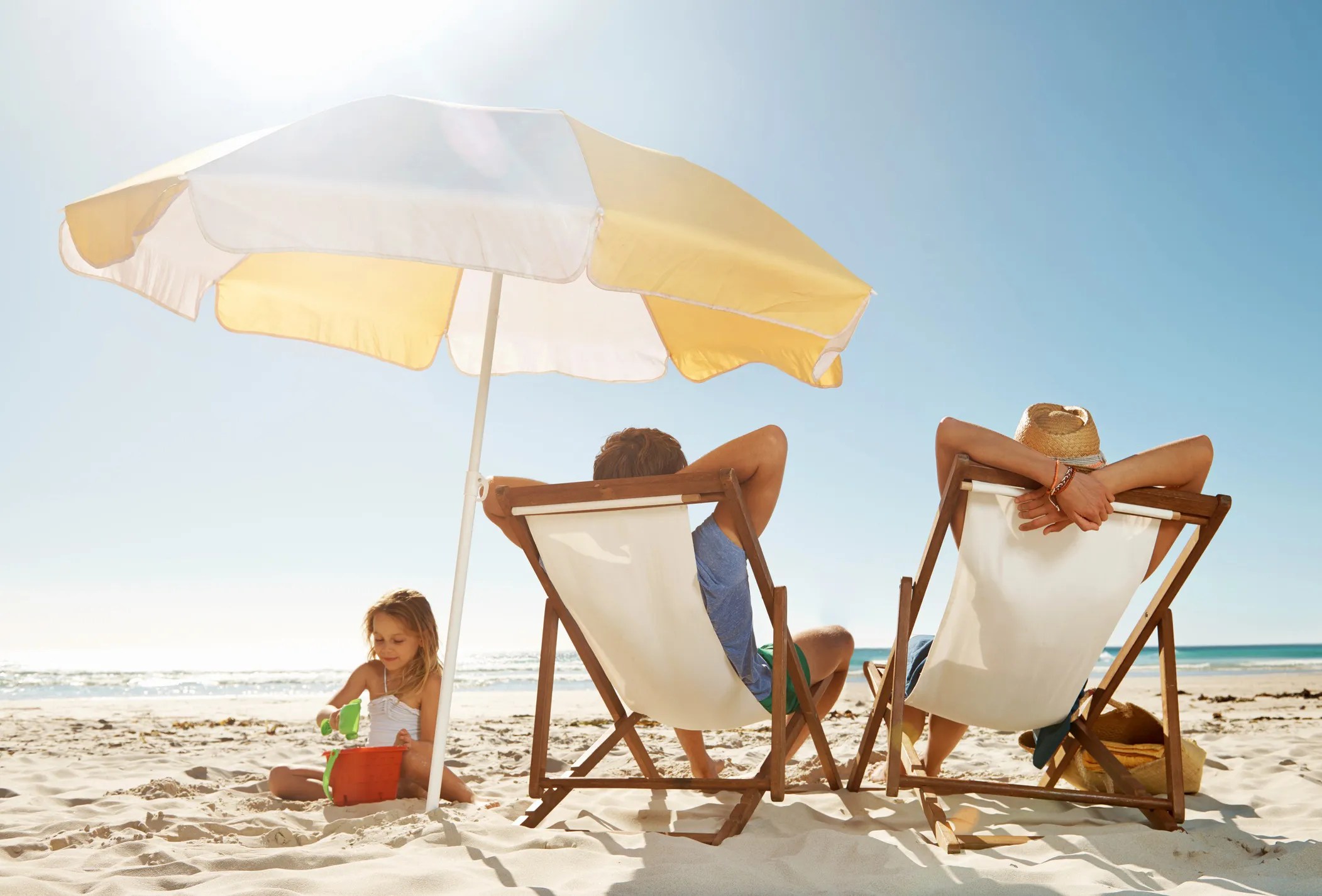 Family sitting under a beach umbrella that adheres to ASTM F3681-24.