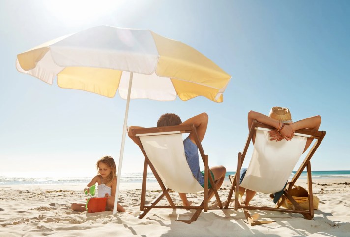 Family sitting under a beach umbrella that adheres to ASTM F3681-24.