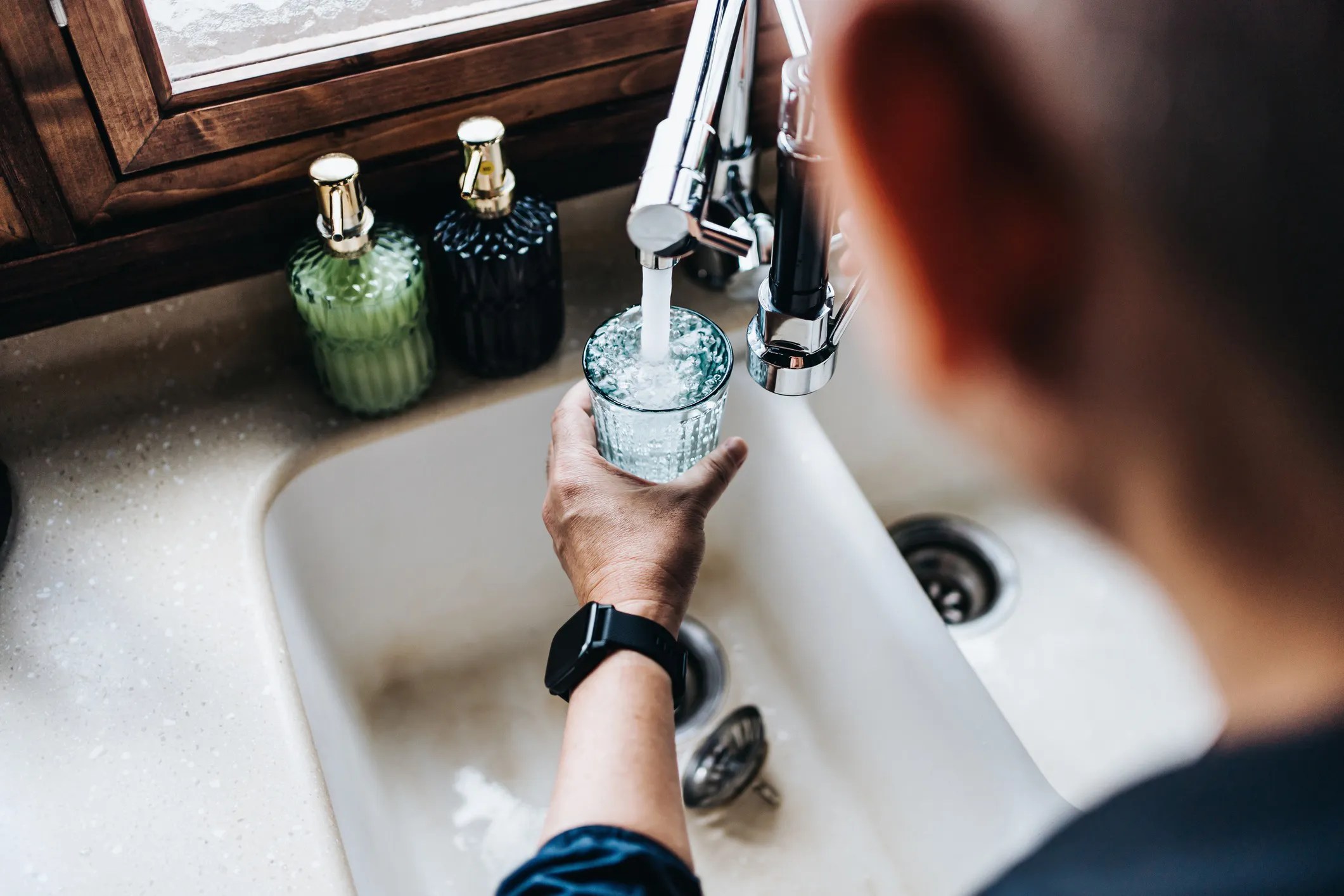 Consumer filling water glass up with drinking water that adheres to NSF/ANSI/CAN 600-2024 guidelines for evaluation chemicals and contaminants in drinking water.