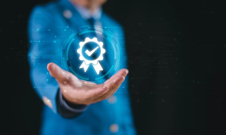 Businessman in blue suit holding digital checkmark to show fully implemented certificate program