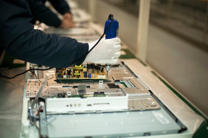 Circuit board being manufactured in a factory that has electrostatic discharge (ESD) awareness symbols that adhere to ANSI/ESD S8.1-2021.