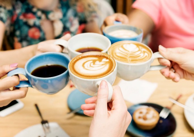 Friends drinking mold-free coffee, tested to ISO/IEC 17025:2017 requirements, at a cafe.