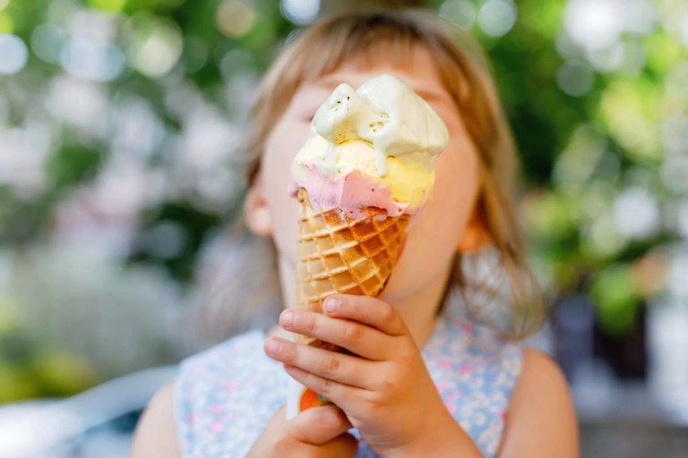 Little girl licking an ice cream cone that adheres to ISO 22000 food safety requirements.