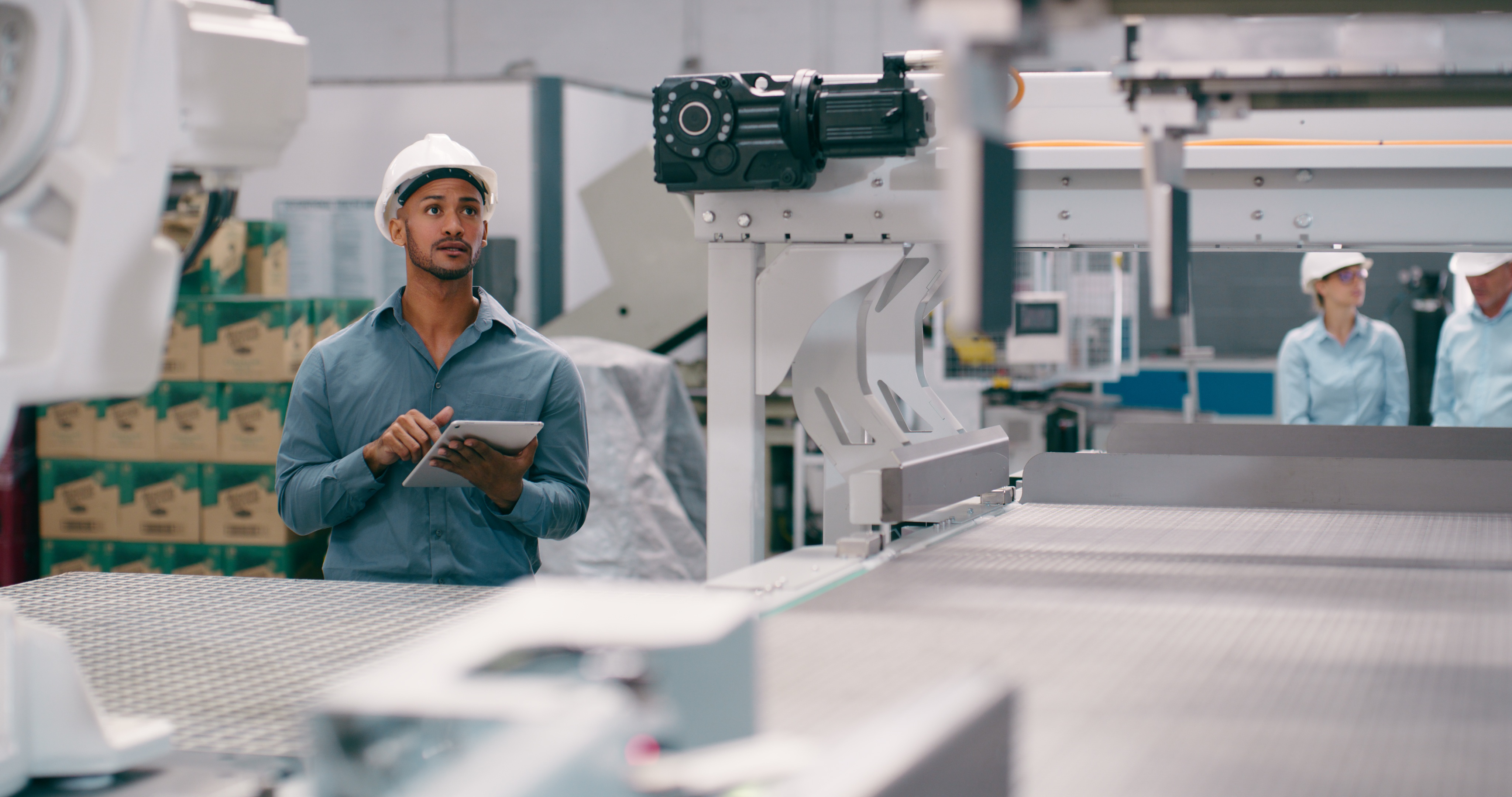 Workers in a manufacturing factory using an IT/OT system integration as defined in the ANSI/ISA 95.00.01-2025 standard for smart manufacturing environments.