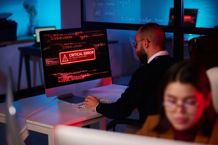 An employee doing work on his computer that has a critical error warning message in red that complies to ANSI Z535.7-2024.