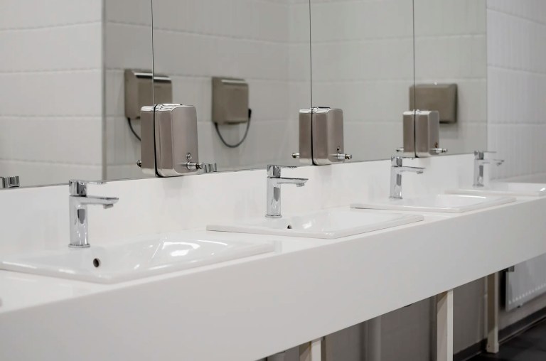 Restroom sinks lined up with chrome faucets.