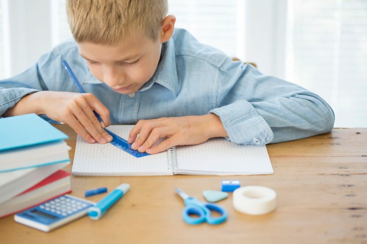 American boy using a ruler, adhering to the imperial measurement system, to do his math homework.