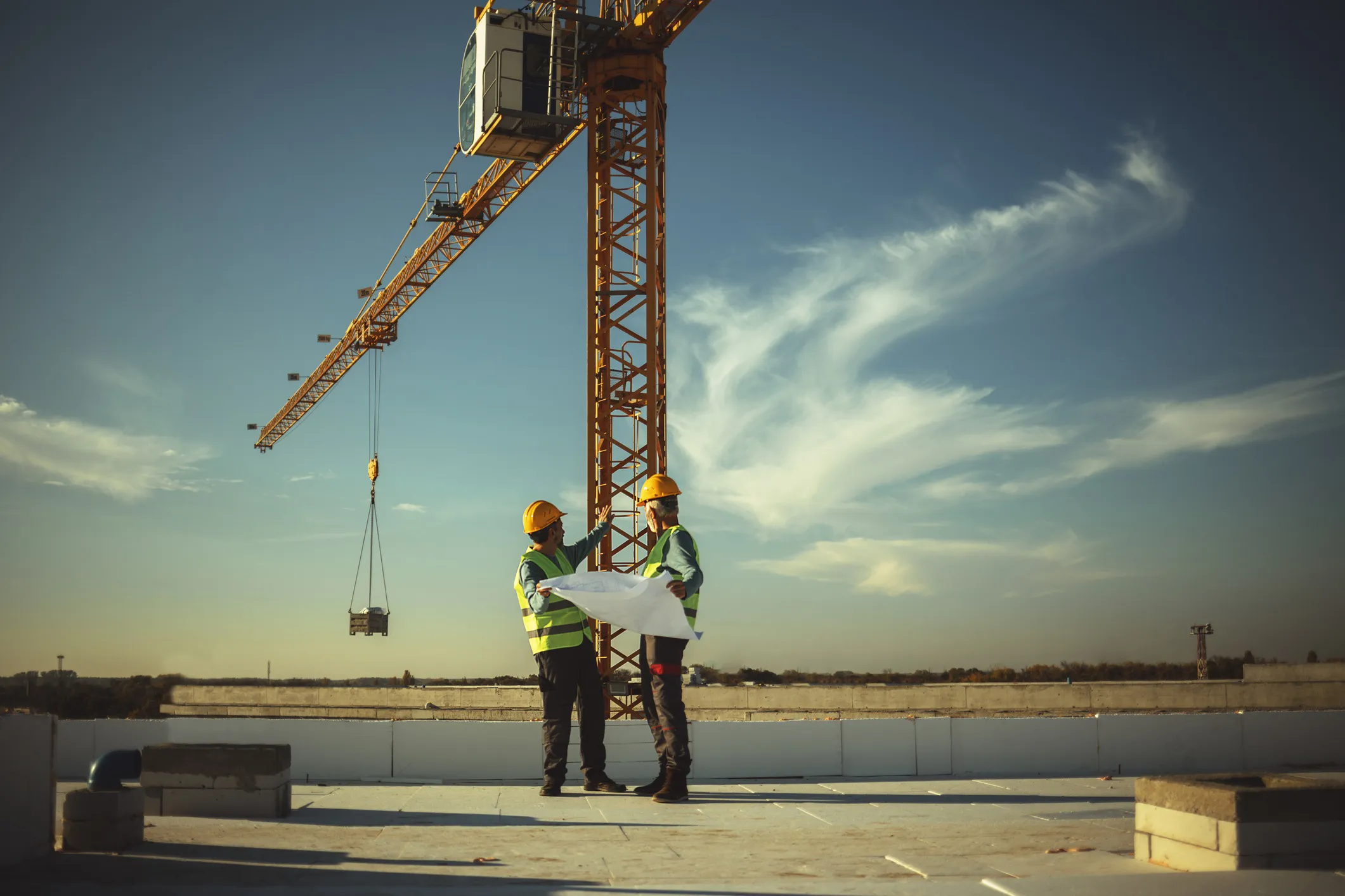 Articulating boom crane lifting materials on a construction site, compliant with ASME B30.22-2023.