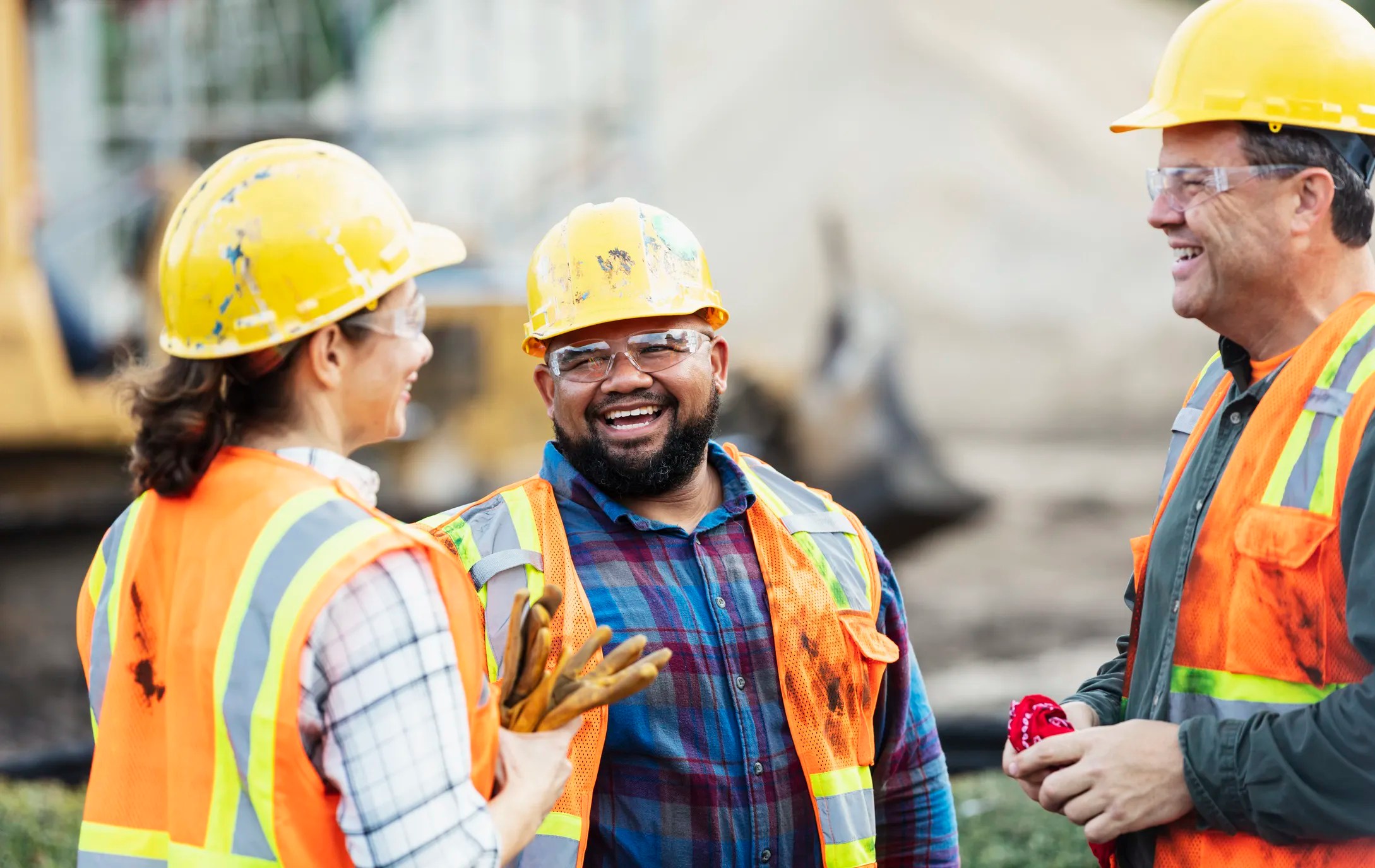 Construction workers wearing high-visibility clothing, safety gloves, and a hard hat—demonstrating compliance with worker safety standards for personal protective equipment.