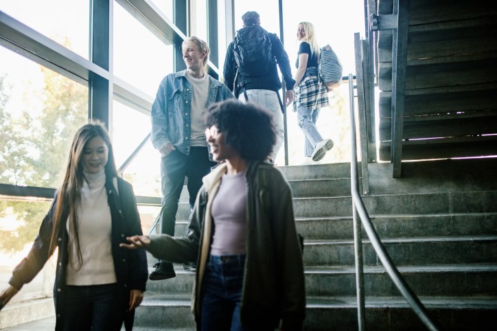 Students walking up stairs in a modern campus building, engaging in conversation.