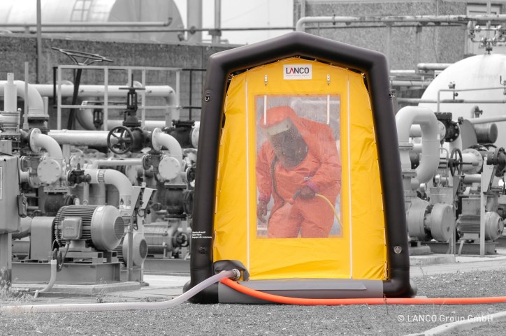 A man in an orange suit exiting orange decontamination chamber tent.