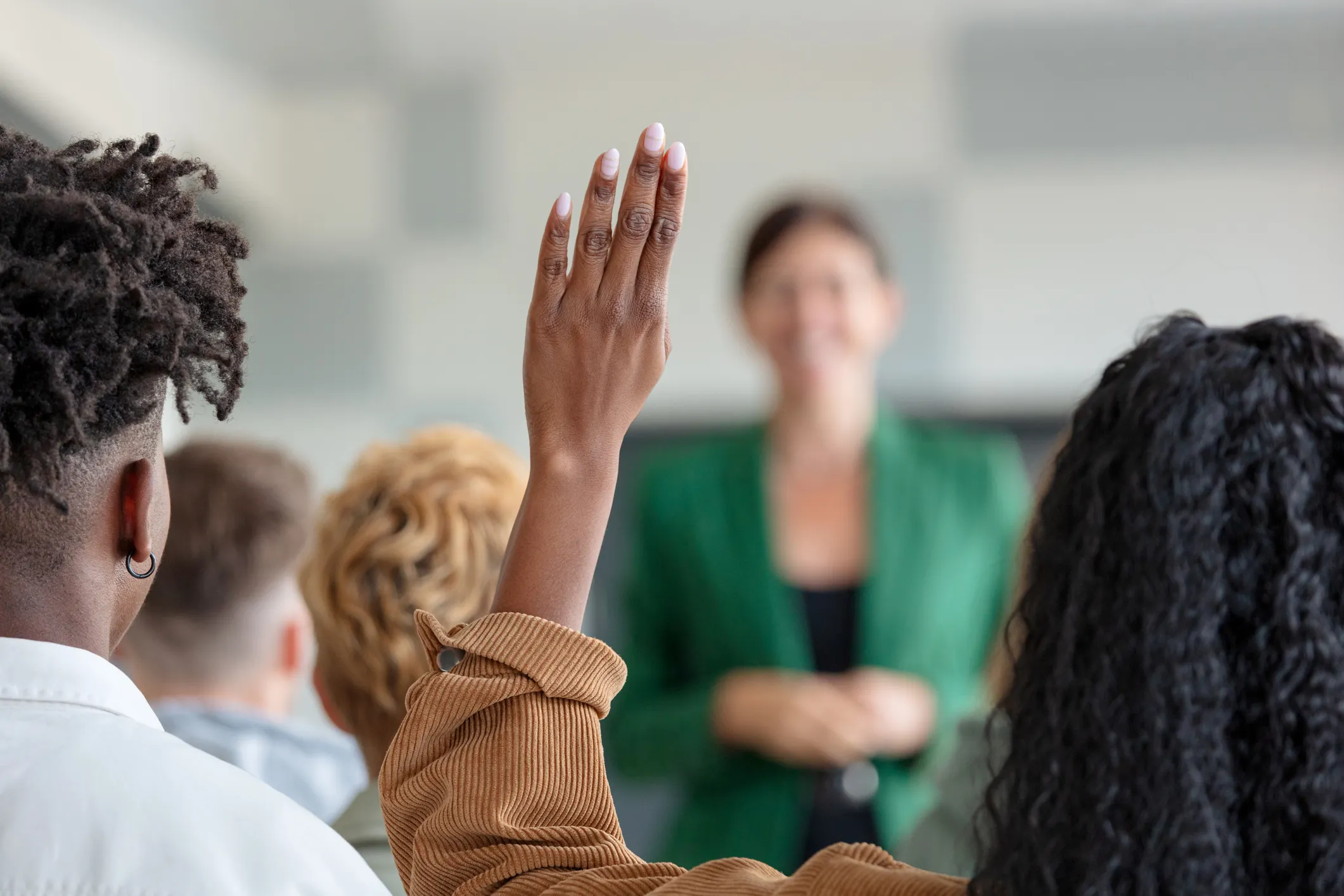 A group of people raising their hands in front of a teacher.