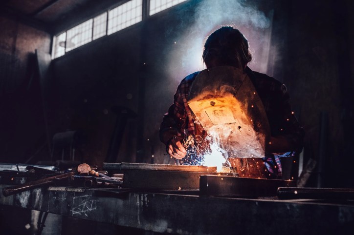 Welding technician performing cast iron repair using preheating and nickel-based filler rod, following AWS D11.89 (R2006) welding procedures.