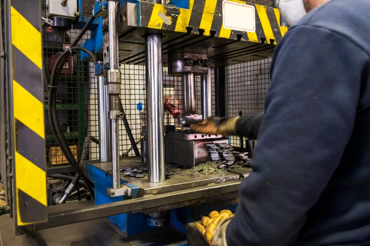 Operator using a CNC power press brake, adhering to ANSI B11.3-2022, to bend sheet metal in a manufacturing facility