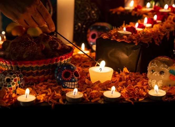 A colorful Día de los Muertos altar (ofrenda) adorned with marigolds, sugar skulls, photos of loved ones, and glowing LED candles. The image reflects the tradition of guiding spirits with light while highlighting the use of IEC 60598-compliant electric candles as a safer alternative to open flames in honoring this meaningful celebration.