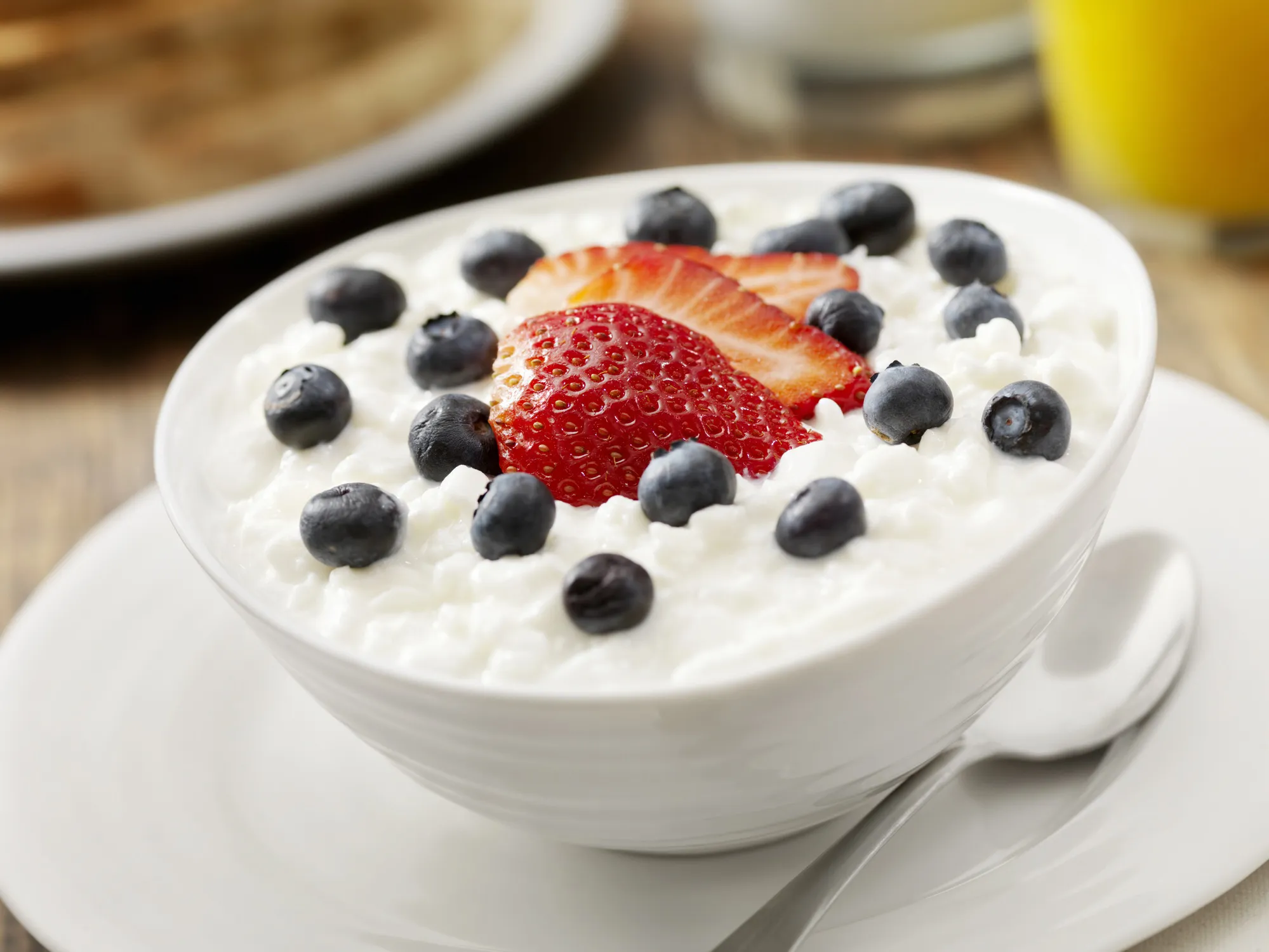 Bowl of cottage cheese with fresh berries representing dairy production safety, quality control, and food safety management in processed foods.