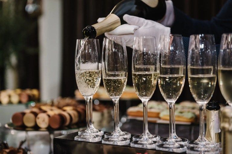 Waiter pouring Champagne into elegant glasses, showcasing sparkling bubbles and celebratory atmosphere during a refined wine tasting or special occasion.