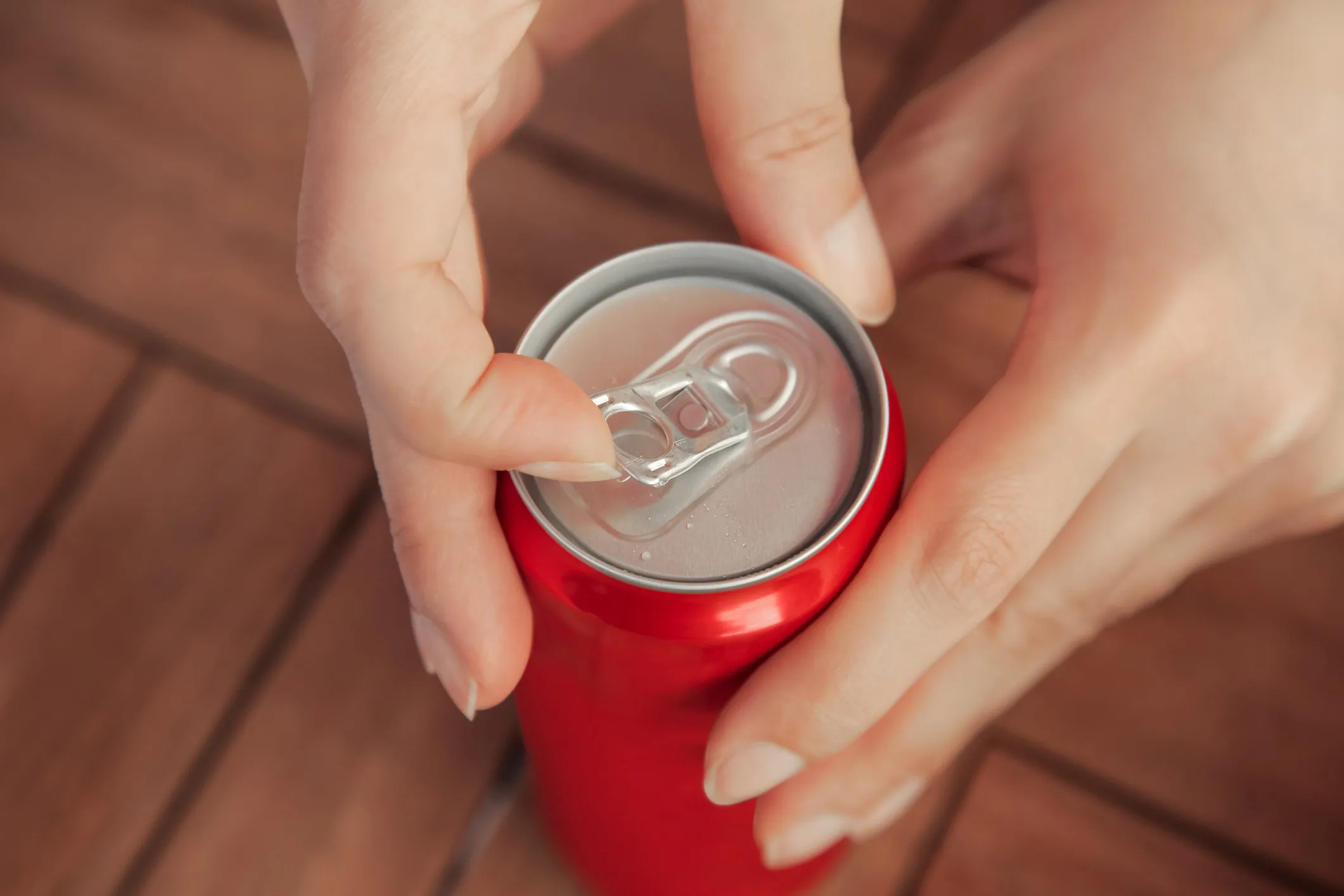 A consumer opening a soda can, showcasing the satisfying sound of the pop that enhances brand experience and influences purchasing decisions.