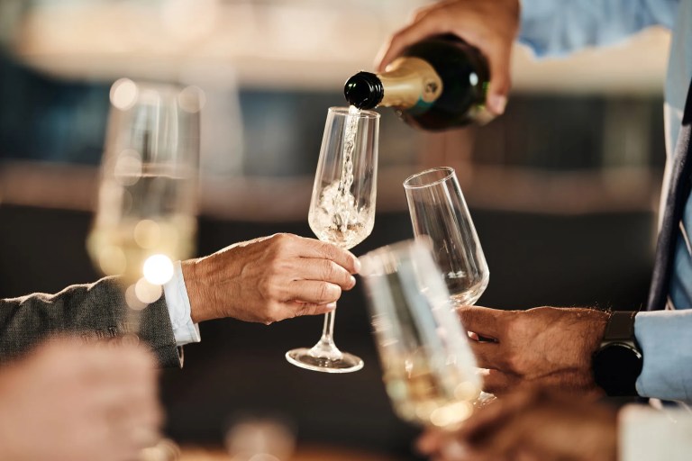 A freshly popped bottle of champagne with golden bubbles rising in crystal flutes, symbolizing celebration, luxury, and the rich history of sparkling wine.