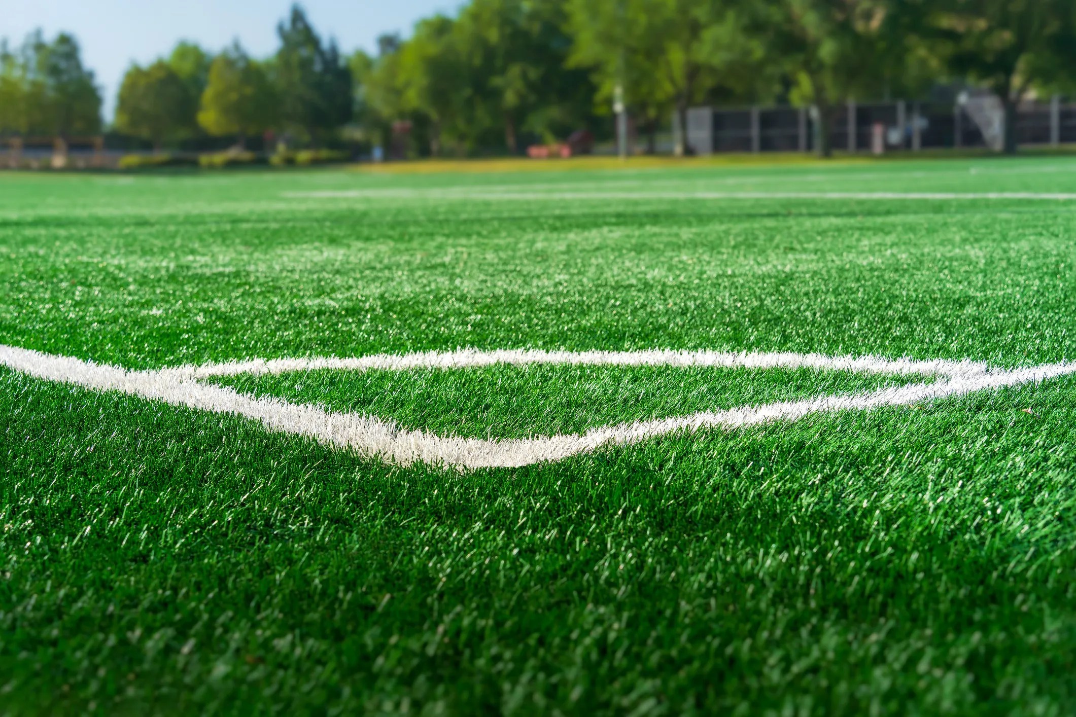 Artificial turf soccer field, adhering to ASTM F1015-03(2017) test methods, with synthetic grass fibers and infill designed for durability, performance, and reduced abrasiveness to enhance player safety during play.