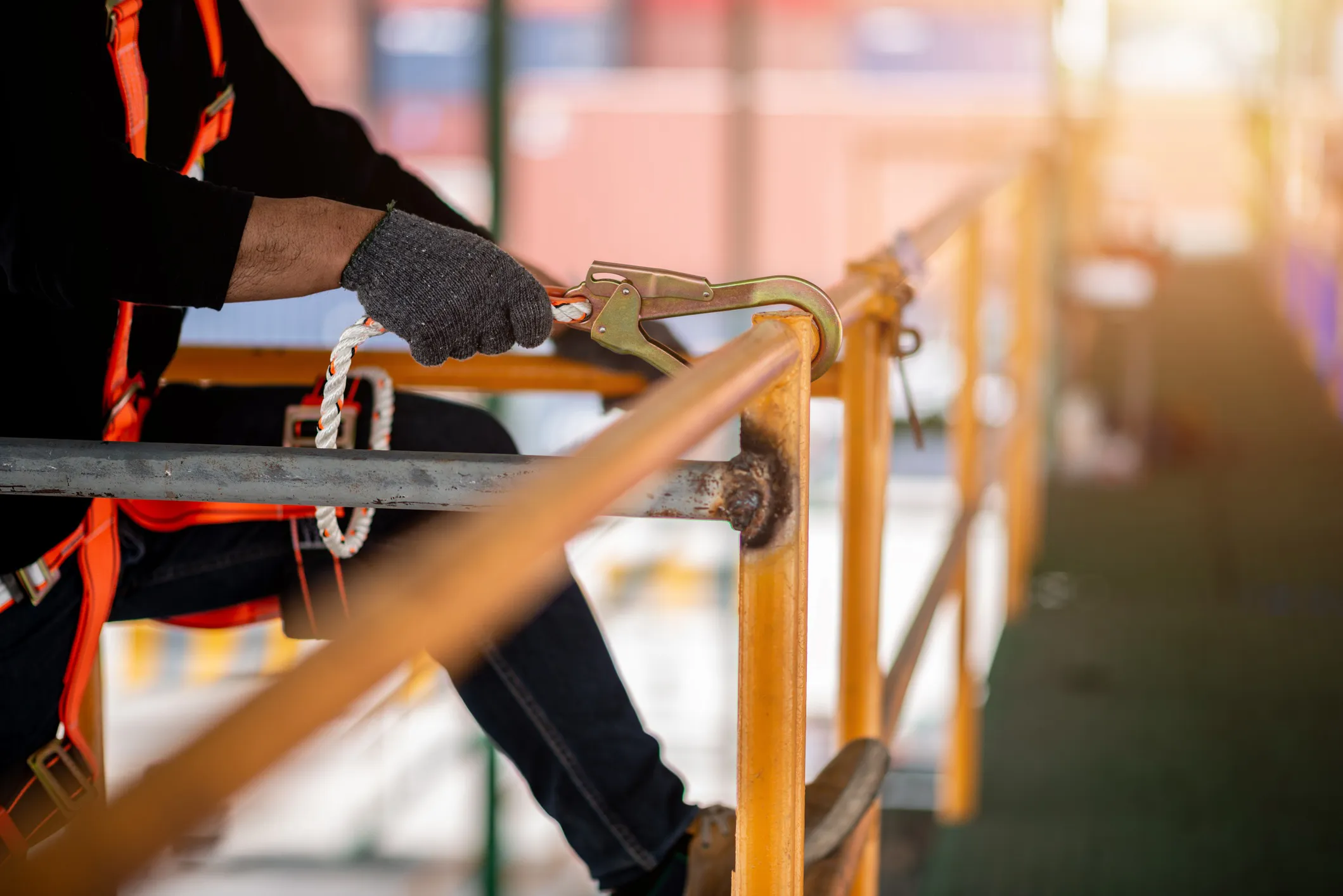 A worker wearing a safety harness and fall protection equipment while working at height on a construction site, demonstrating proper safety measures to prevent OSHA fall-related violations.