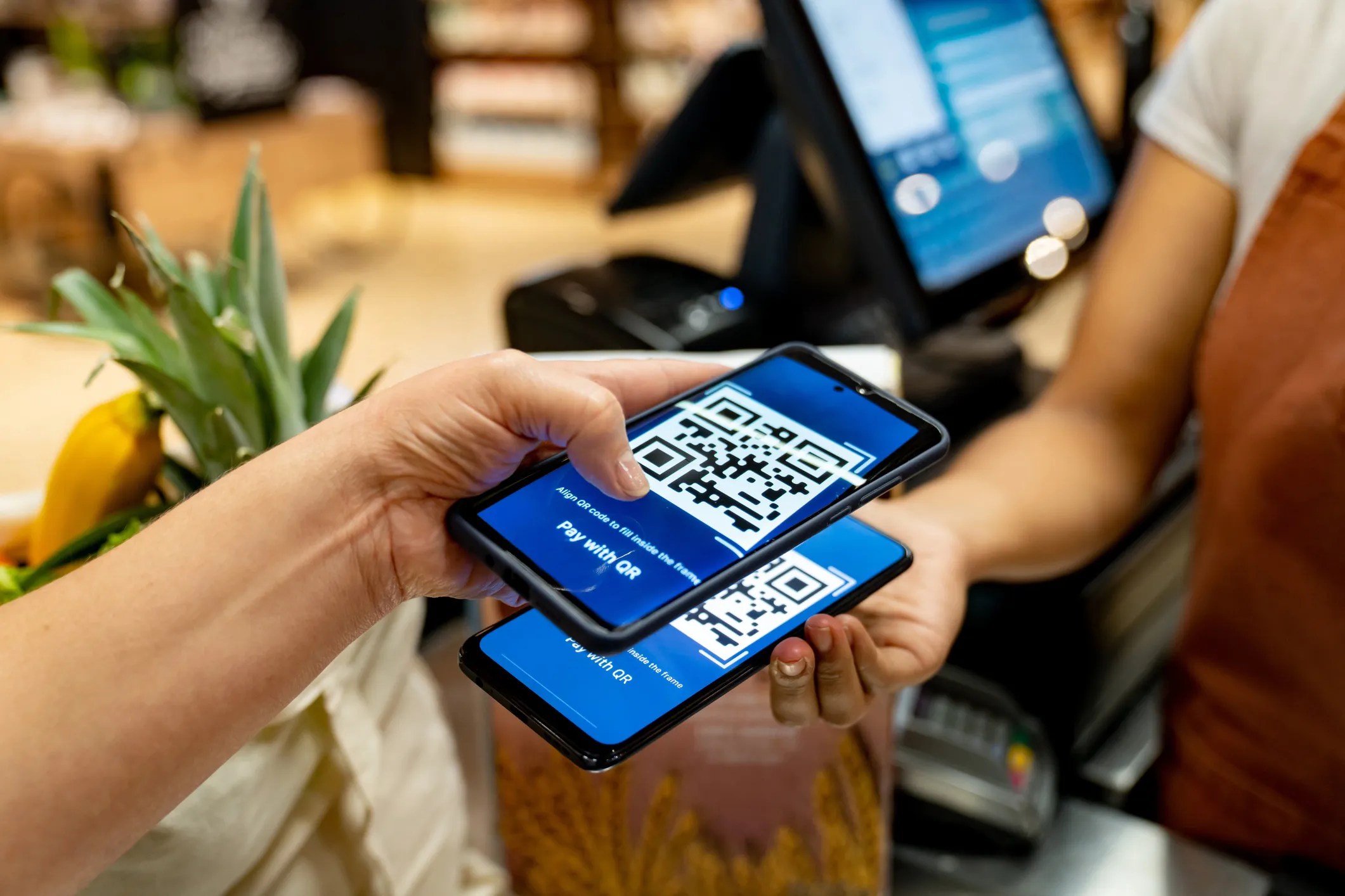 Customer making a mobile payment through a smart phone by using a QR code that adheres to ISO/IEC 18004:2024.