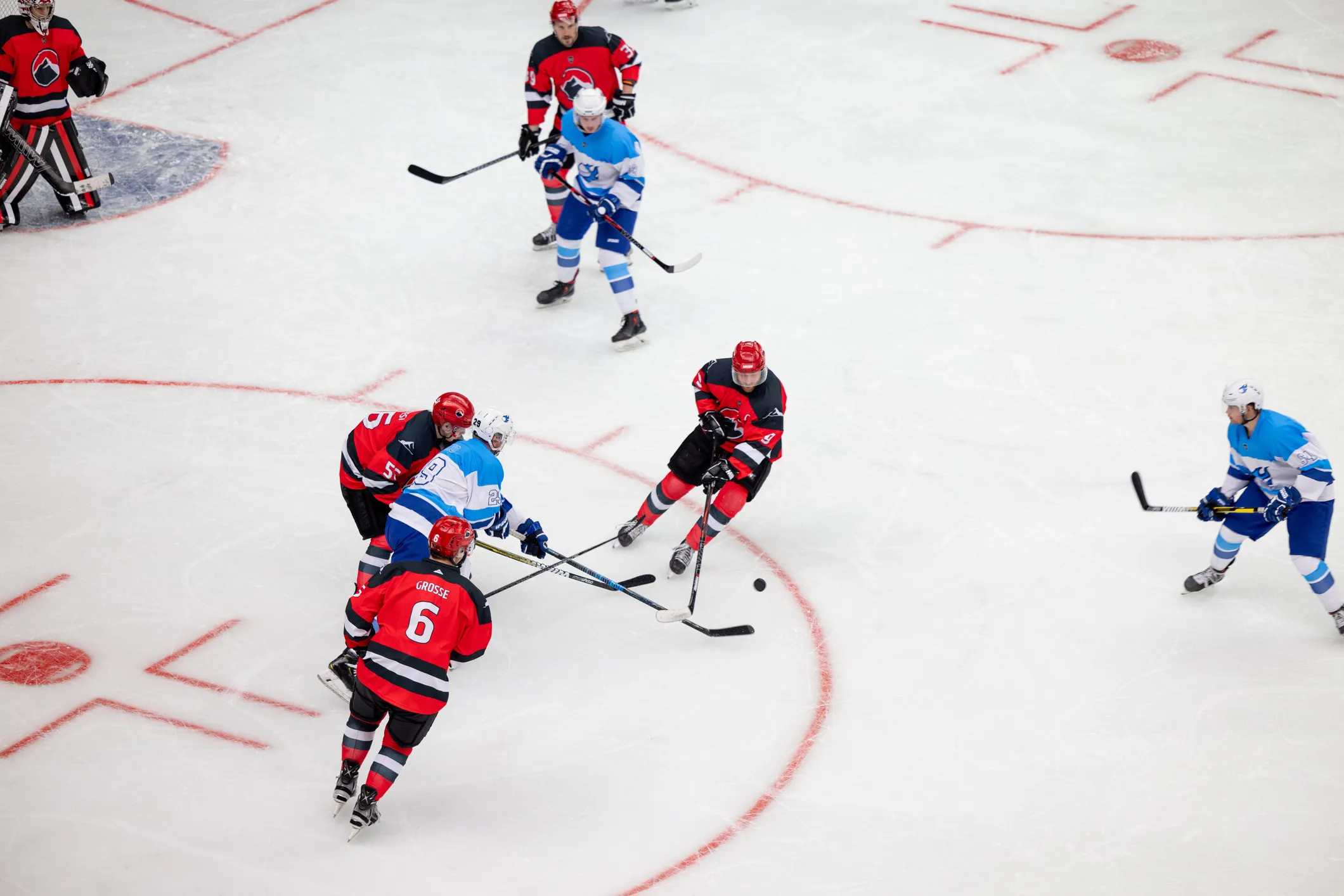 Ice hockey players wearing helmet, face mask, neck guard, and full protective gear during gameplay in compliance with ISO 10256-1:2024.