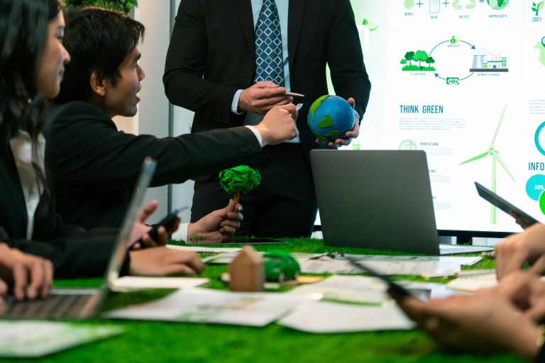 Businessman leader giving presentation on eco-friendly implementation in order to reduce CO2 emission and make sustainable ecology for greener future with corporate environmental regulation, adhering to ISO 14001:2026.