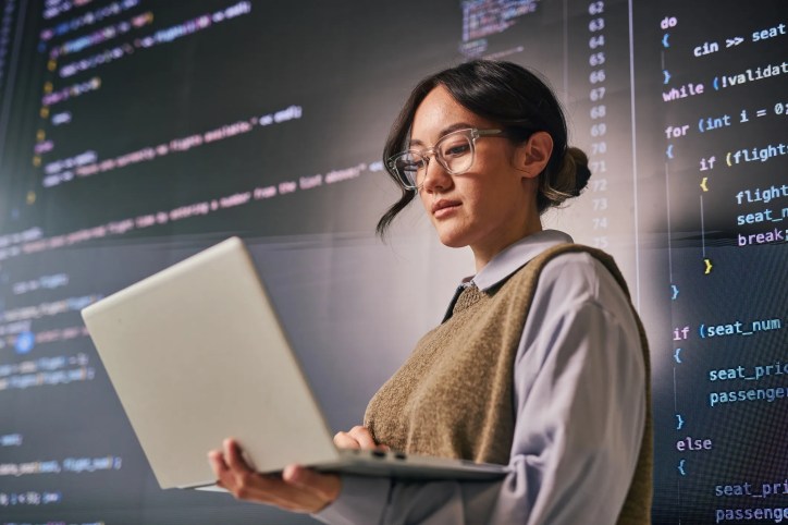 Female software engineer examining the evolution of artificial intelligence from early computing and the Turing Test to modern generative AI and future technologies like autonomous systems and robotics.