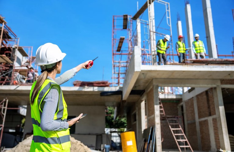 Construction workers using fall protection and scaffolding in compliance with ANSI/ASSP A10 safety standards on a jobsite.