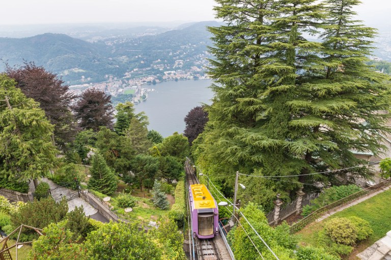 Funicular railway, adhering to ANSI B77.2-2025, ascending a steep hillside with passengers, showcasing safe and efficient cable-based transportation engineering.
