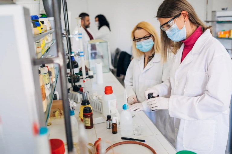 Forensic laboratory scientists reviewing quality management documents and compliance checklist aligned with ANAB accreditation and ISO/IEC 17025, ensuring no nonconformities.