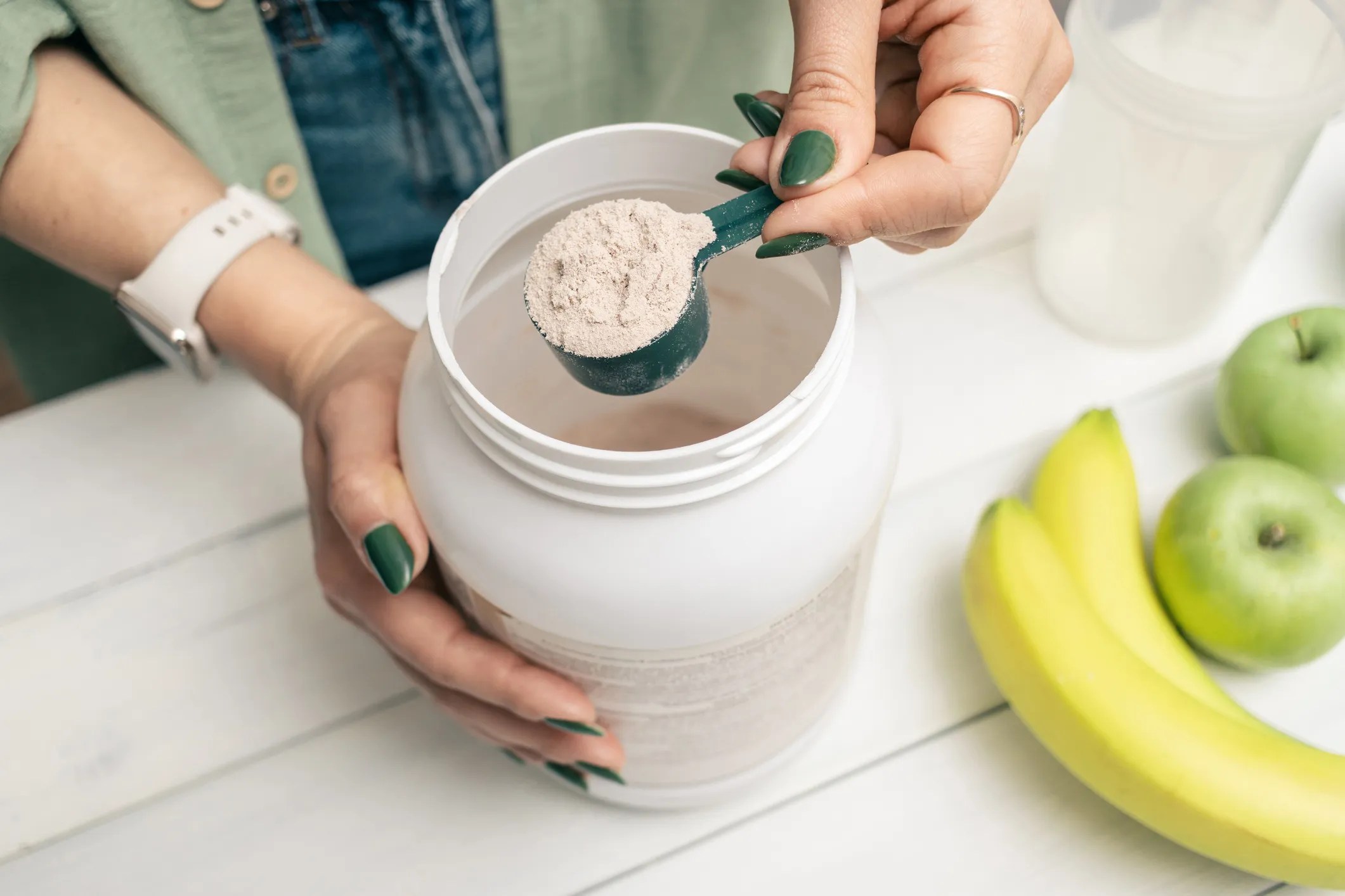 Person adding protein powder to a smoothie illustrating dietary supplement use, safety considerations, and NSF/ANSI 173 compliance.