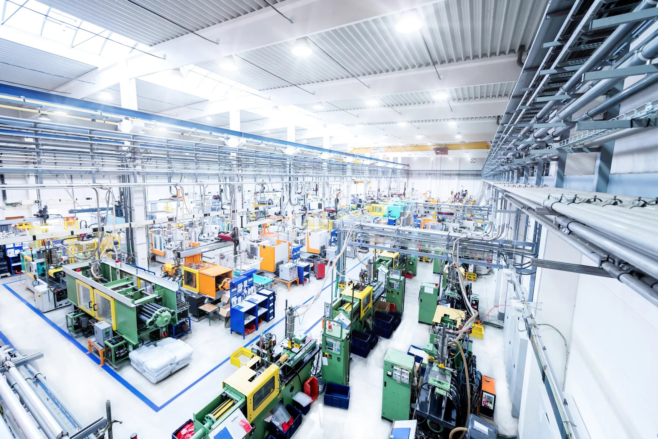 Green machines spread about in bright factory.