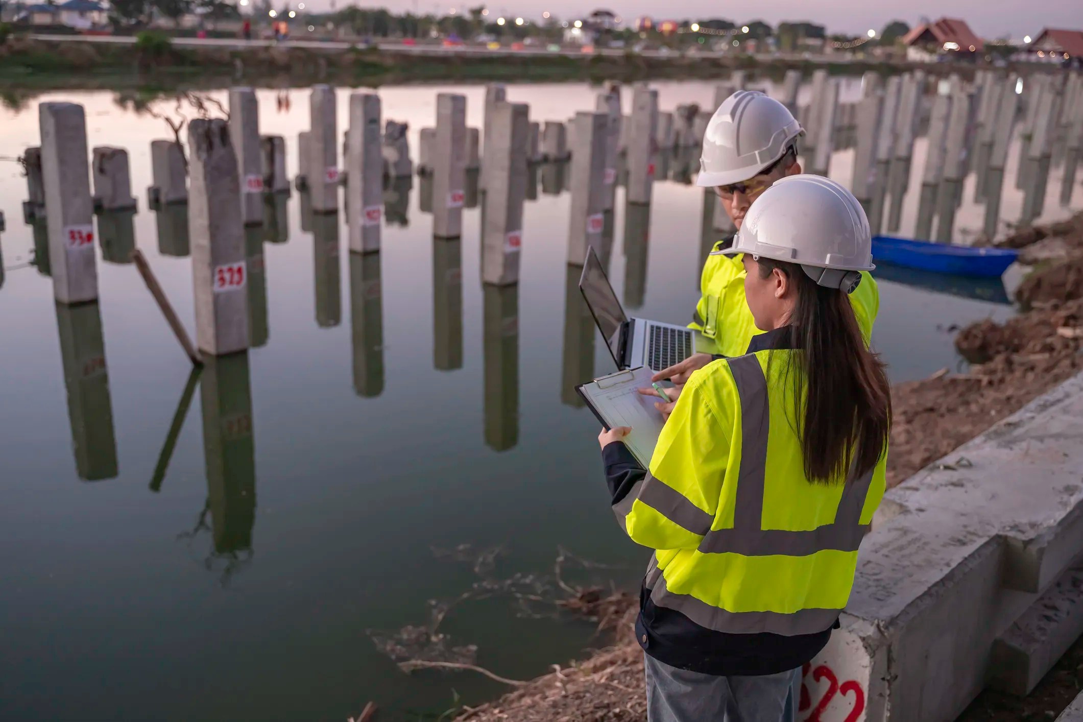 Engineers inspecting a pile foundation construction site with deep foundation piles supporting a large structure, assuring adherence to ASCE 20-96 guidelines.