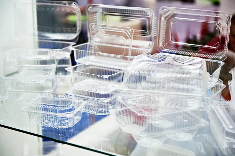 Close-up of compostable plastic food containers, utensils, and packaging made from plant-based materials adhering to ASTM D6400-23.
