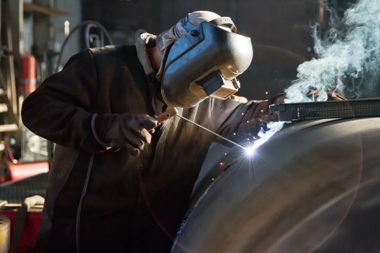 Welder performing arc welding while following AWS B2.1/B2.1M:2026 welding procedure qualification requirements for quality and compliance.